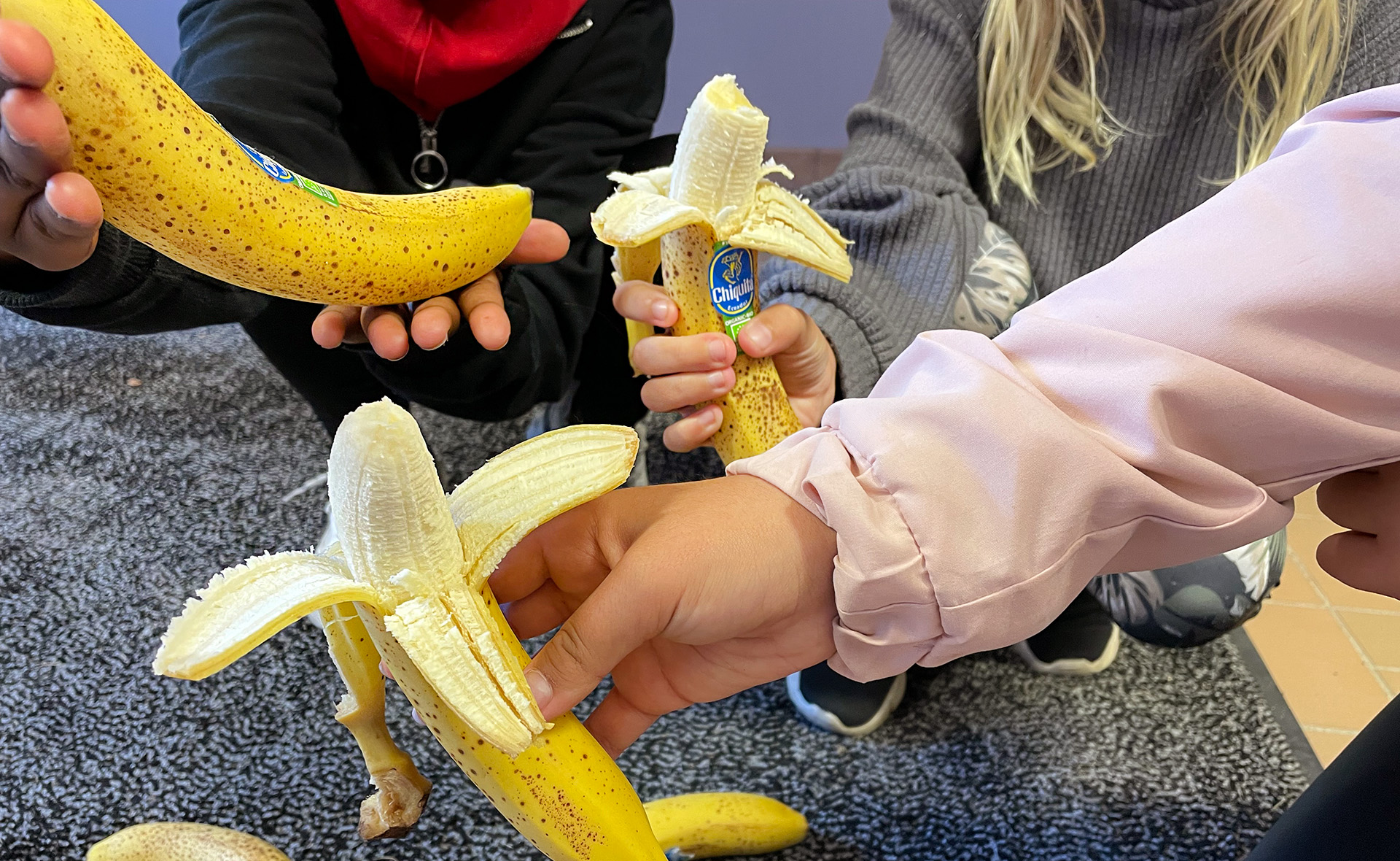 Tre elever håller i bananer