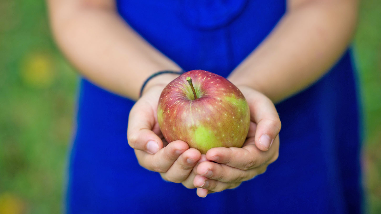 En persons händer syns, personen håller i ett äpple.