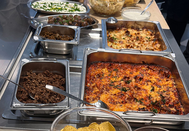 Tillagade maträtter upplagda i kantiner på ett serveringsbord.