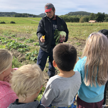 Lokal odlare visar grönsaker och odlingar för några skolbarn.