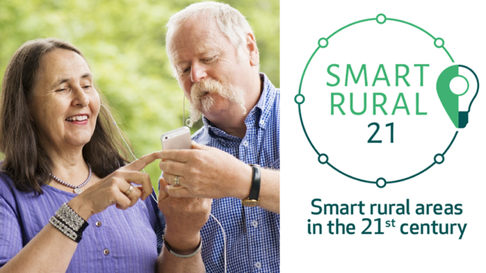 En kvinna och en man tittar på en mobiltelefon. Till höger syns Smart Rural 21:s logga.