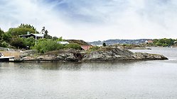 Skärgårdsmiljö med en bebyggd kobbe i förgrunden.