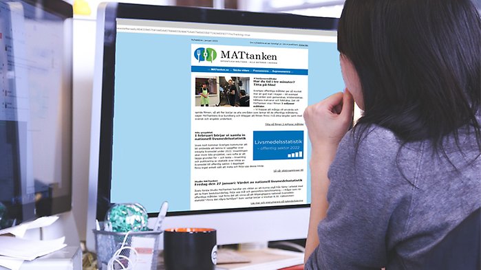 Kvinna sitter vid dator. MATtankens nyhetsbrev syns på skärmen.