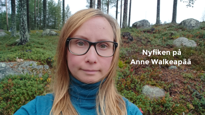 På bilden syns Anne Walkeapää. Hon står i skogen och har en blå polotröja och svarta glasögon på sig. 