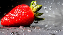 En röd jordgubbe med färskt vatten som stänker
